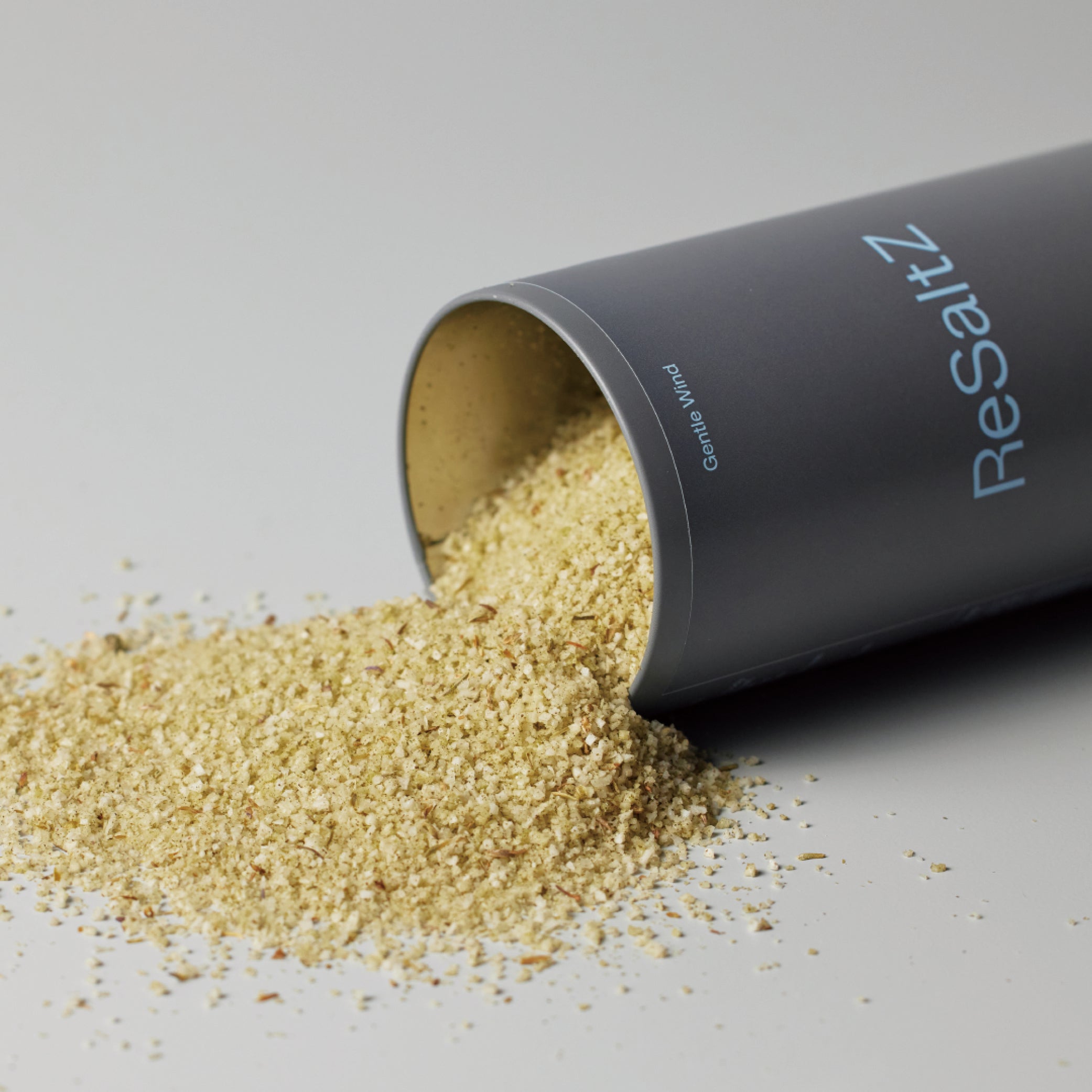 ReSaltZ Gentle Wind bath salts spilling out from a tin case, showcasing the fine, natural salt granules