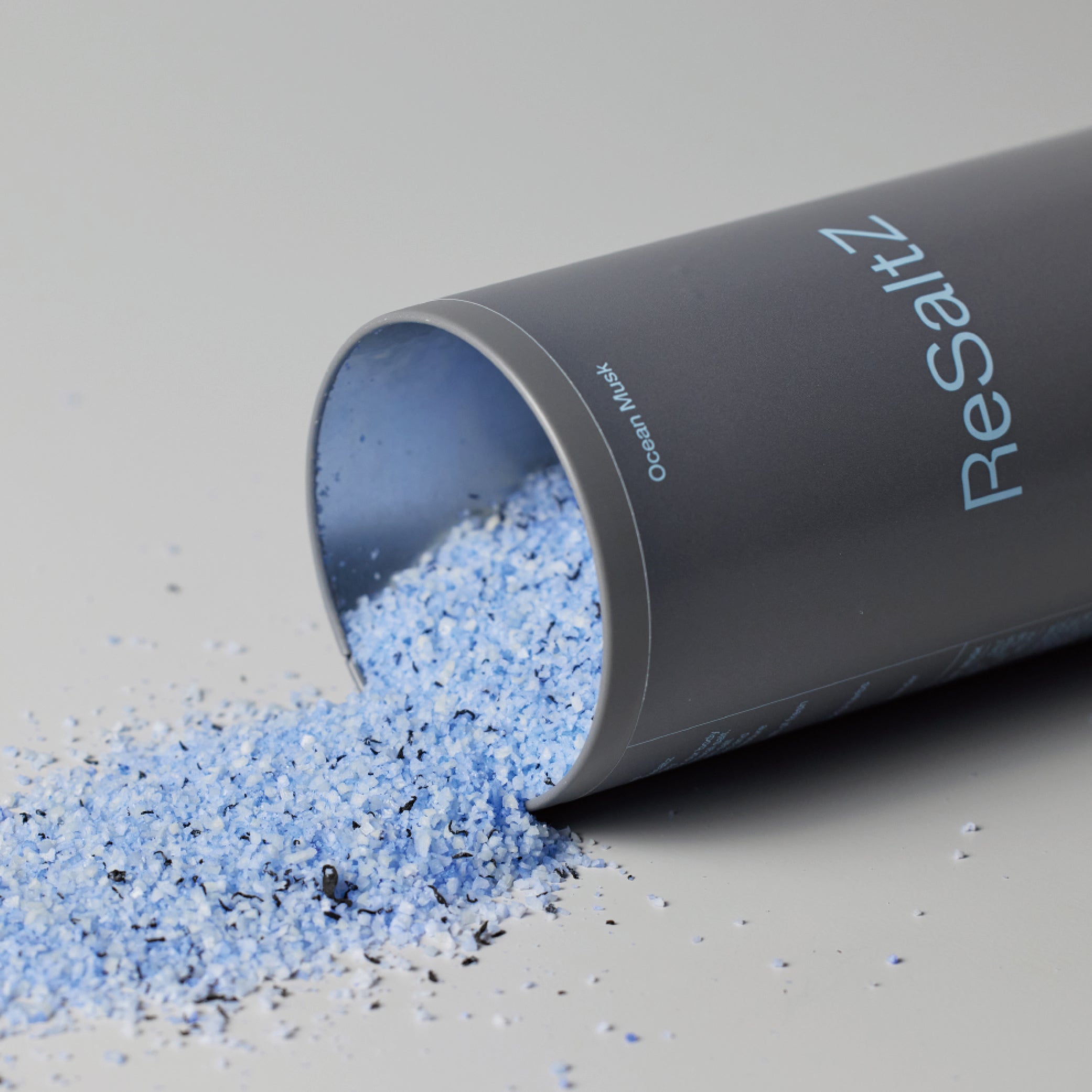 The tin case is lying on its side on the floor, with ReSaltZ blue bath salts spilling out onto the floor.