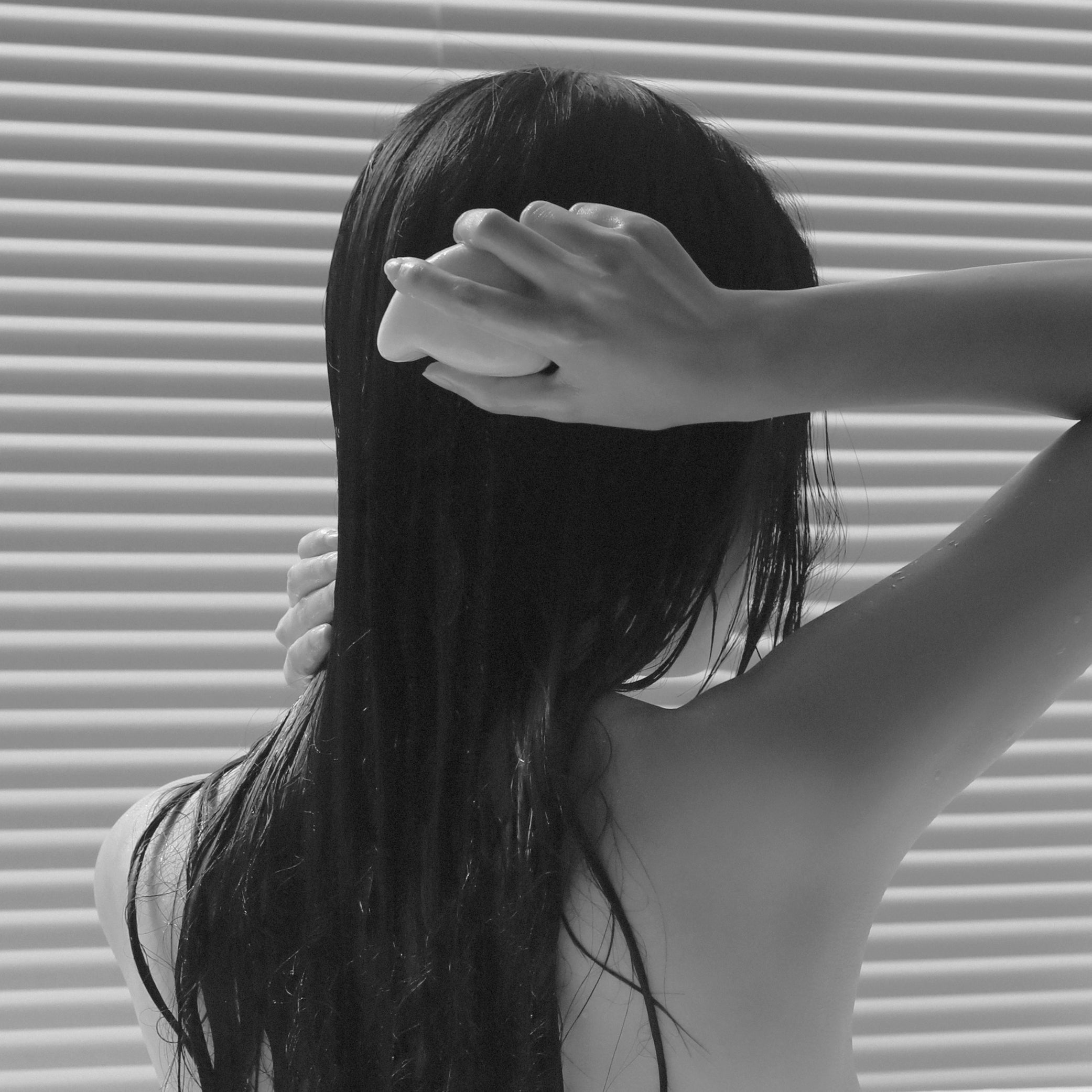 One hand gently holding the Salt Massage Hair Conditioner, with a tender touch as it lathers into the hair, evoking a sense of serene self-care and indulgence