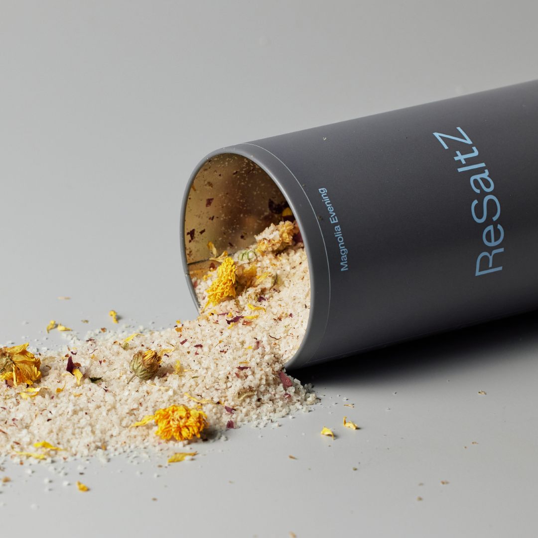 ReSatlZ Aroma Bath Salt Magnolia Evening with yellow dried flowers. Magnolia Evening includes delicate petals, creating a calming and luxurious presentation.
